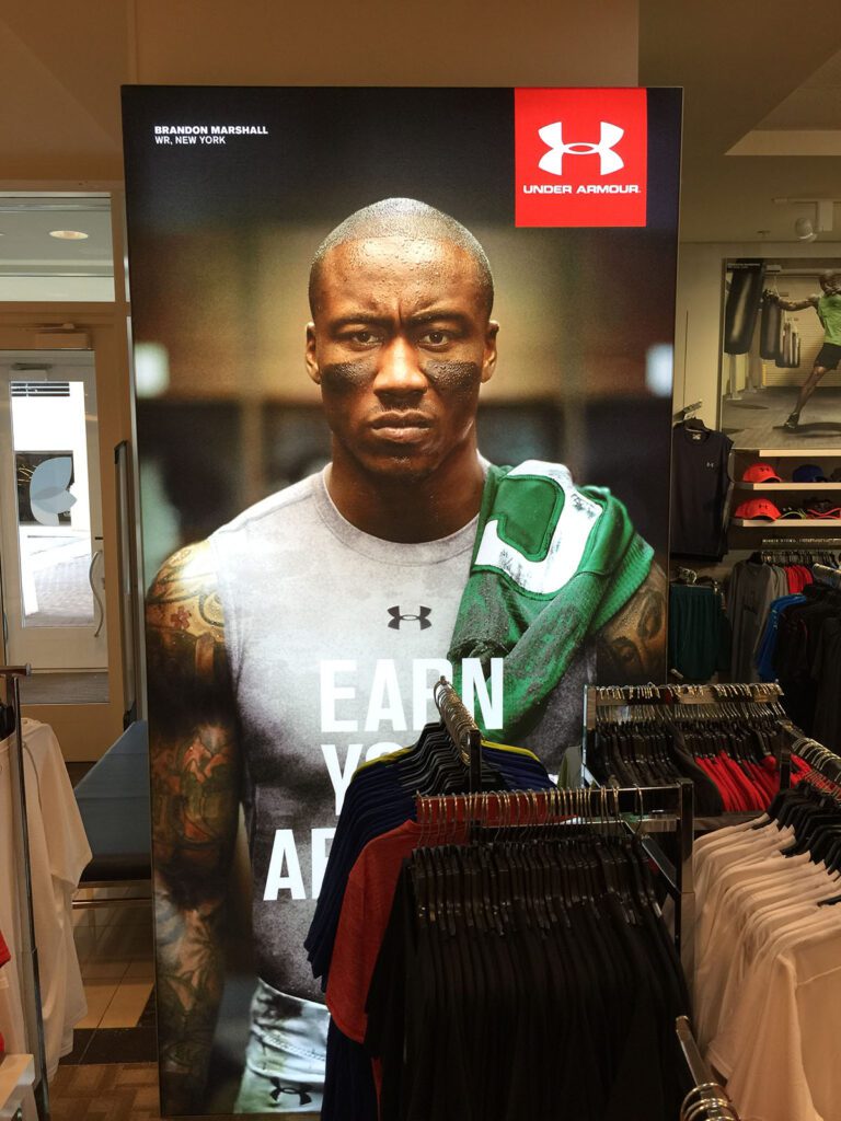 image features a large display showcasing Brandon Marshall, a former NFL wide receiver, as part of an Under Armour advertisement